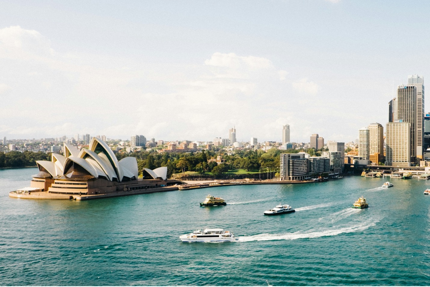 Skyline view of Sydney, Australia near a lake with multiple boats in the water.